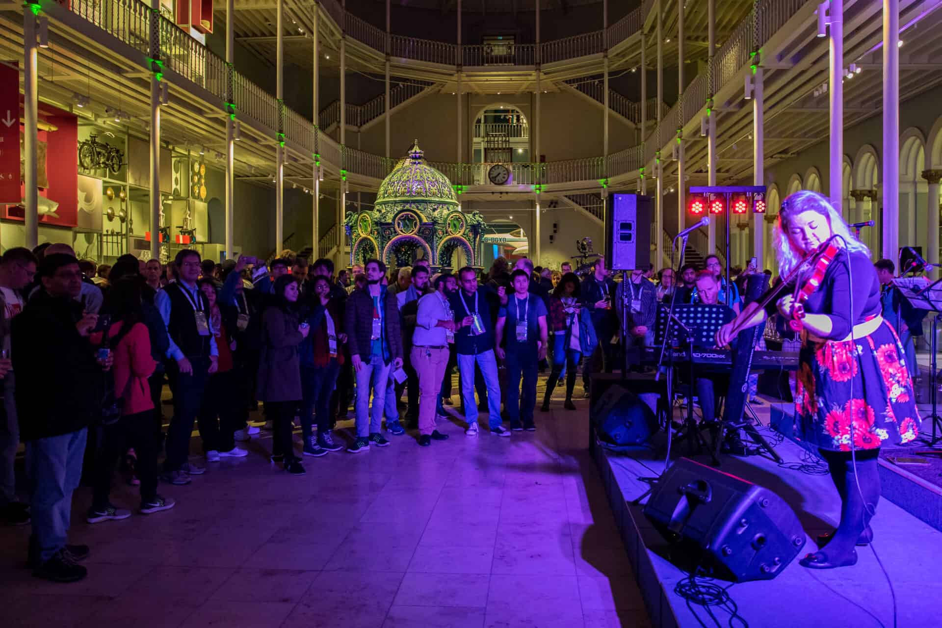 Woman plays violin surrounded by a crowd of people.