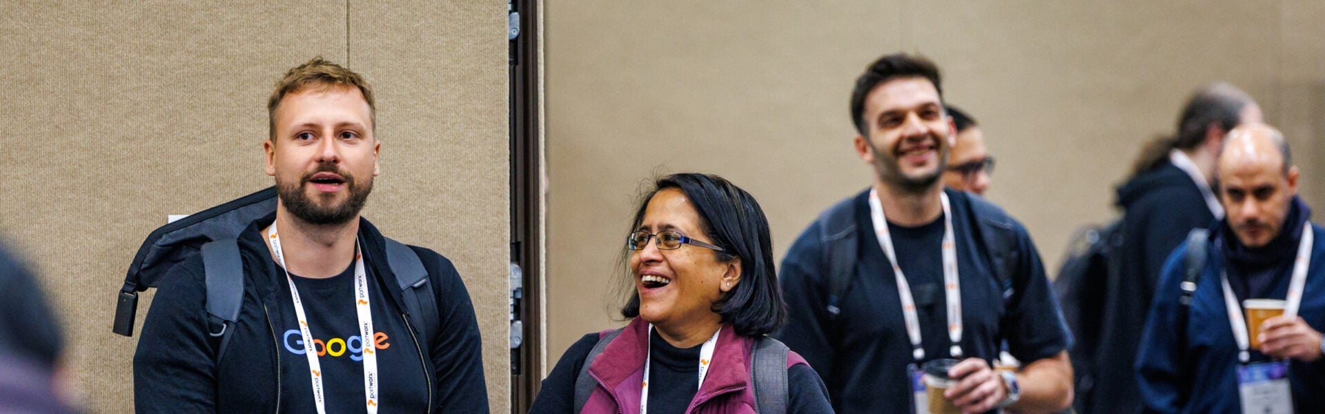 Attendees holding coffee cups and talking and laughing with each other.